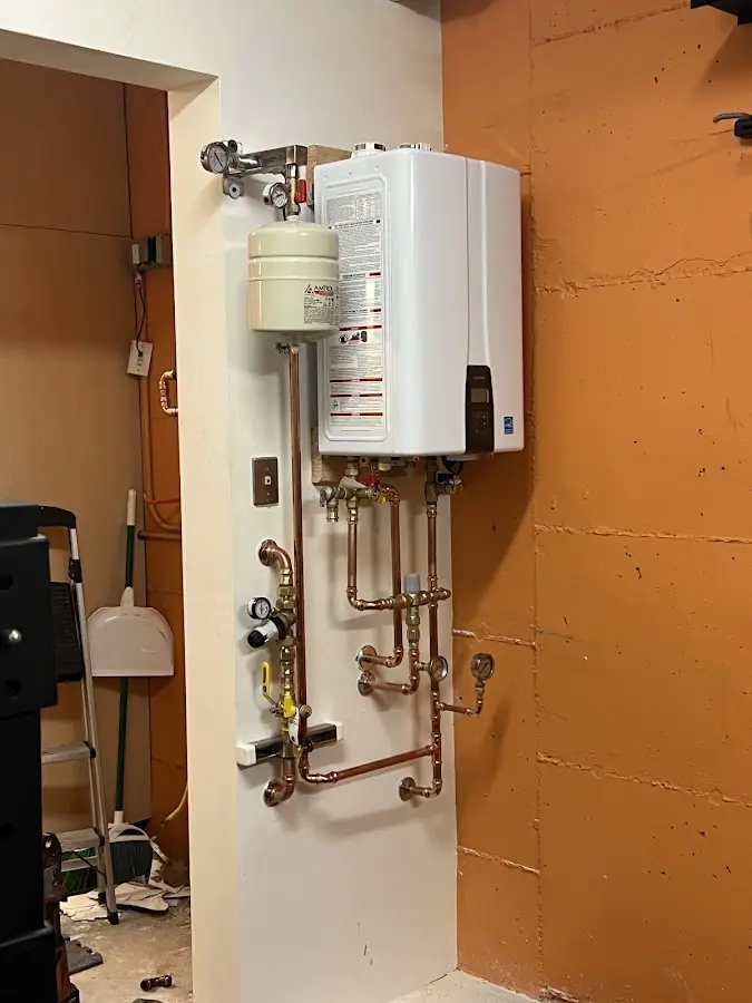 Plumbing technician inspecting water heater connections in Franklin